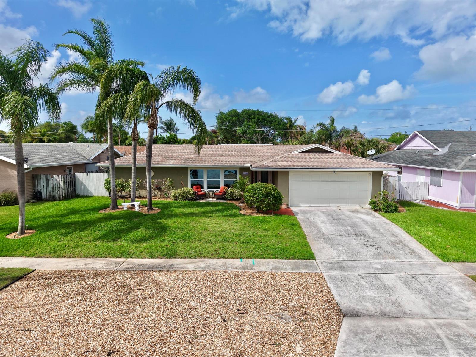 A single-story house with a tan exterior, a two-car garage, and palm trees in the yard — 4167 Russell Street, Jupiter FL 33469, JUPITER, FL