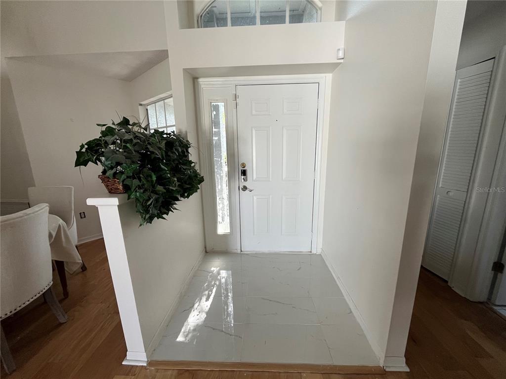 An entryway features white tile flooring, a white front door with a sidelight, and a plant — 2930 SHANNON CIR, PALM HARBOR, FL
