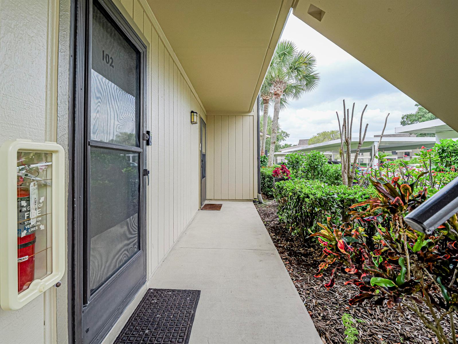An exterior walkway leads to the front door of unit 102, featuring a fire extinguisher — 23 Plantation Drive # 102, Vero Beach FL 32966, VERO BEACH, FL