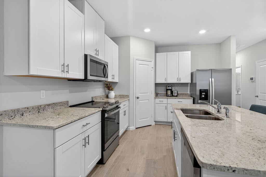 A kitchen features white cabinets, granite countertops, stainless steel appliances, and a central island — 5696 SE Edgewater Circle, Stuart FL 34997, STUART, FL