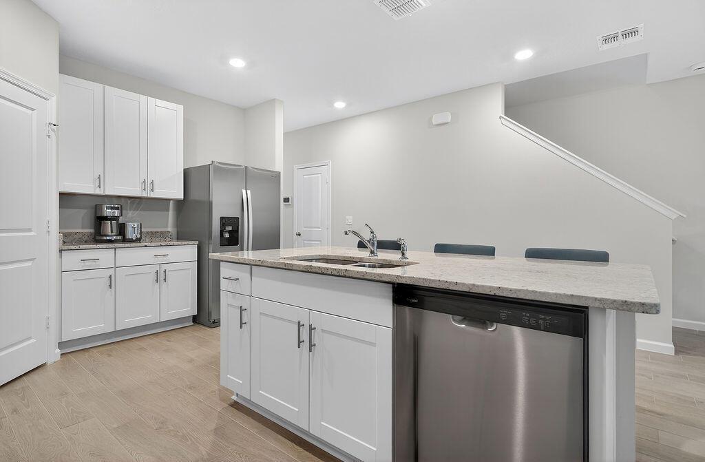 A modern kitchen features white cabinets, granite countertops, stainless steel appliances, and a central island — 5696 SE Edgewater Circle, Stuart FL 34997, STUART, FL