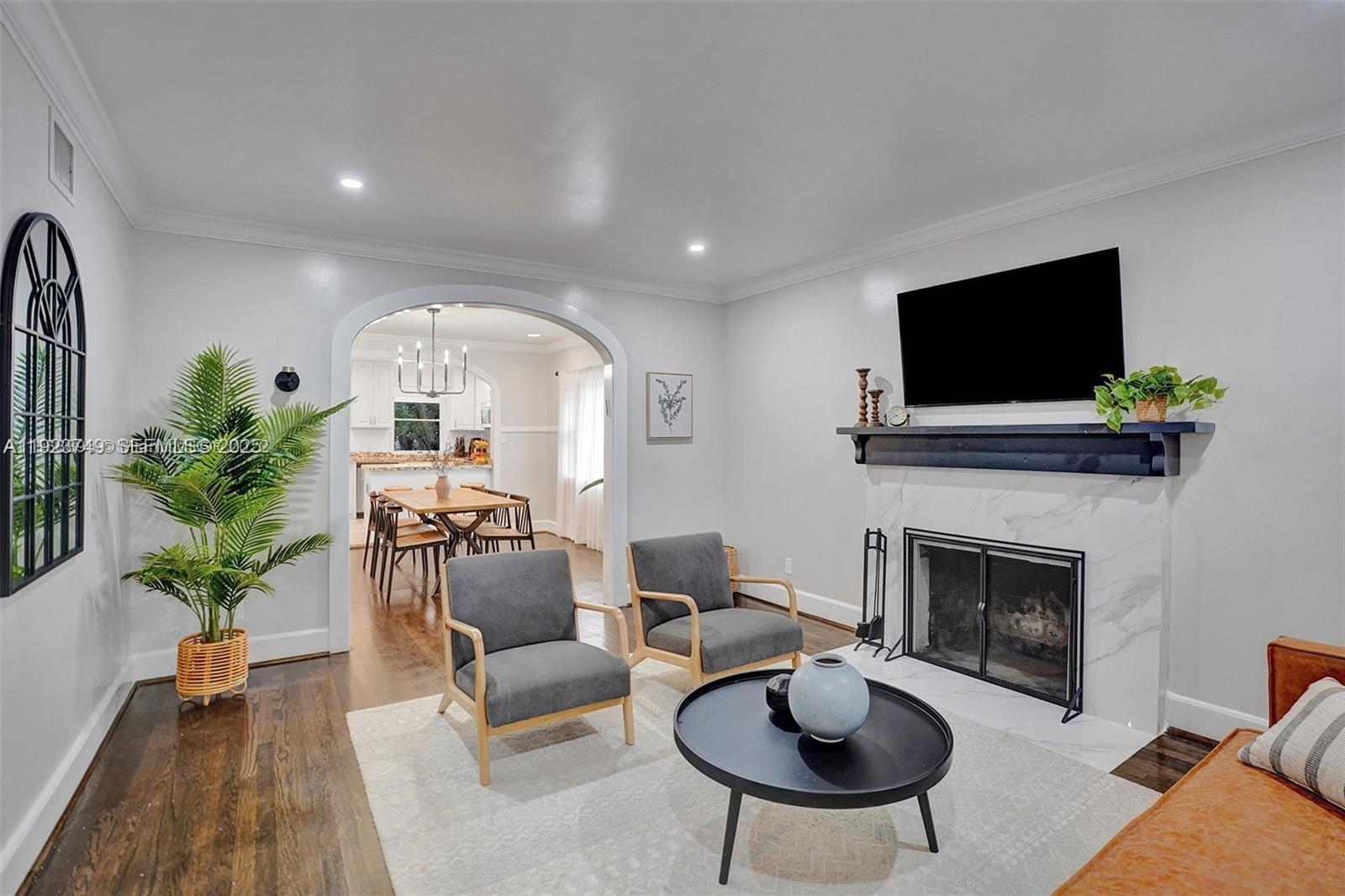 A living room features a marble fireplace, two gray armchairs, and an arched entryway — 1640 Jefferson St, Hollywood FL 33020, HOLLYWOOD, FL