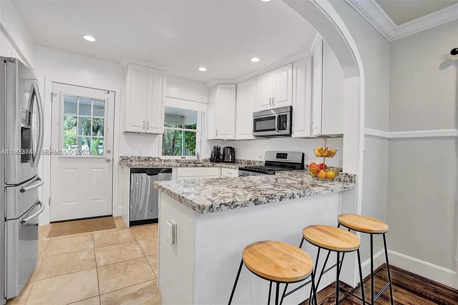 A kitchen features white cabinets, granite countertops, stainless steel appliances, and a breakfast bar — 1640 Jefferson St, Hollywood FL 33020, HOLLYWOOD, FL