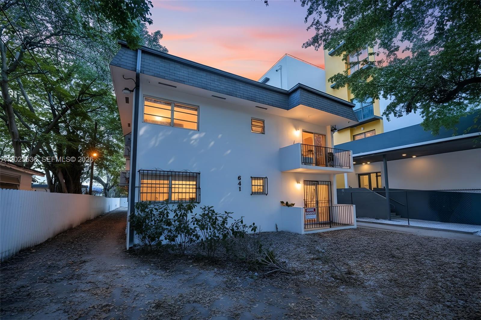 A two-story white building with a balcony and dark trim stands at dusk — 641 NW 2nd St, Miami FL 33128, MIAMI, FL