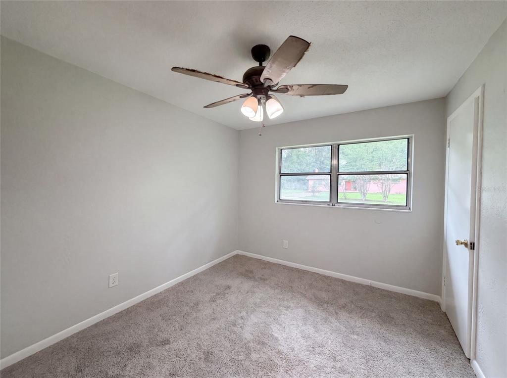 A bedroom with gray walls, gray carpet, a ceiling fan, and a window — 2410 NE 3RD AVENUE, OCALA, FL