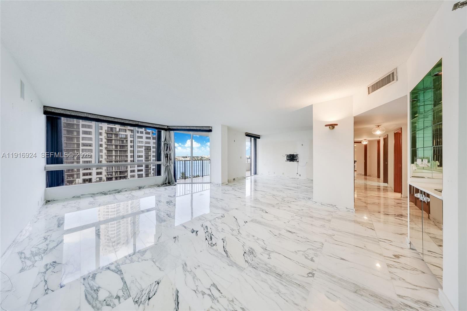 A spacious living area features white marble floors, floor-to-ceiling windows, and a water view — 520 Brickell Key Dr # A1104, Miami FL 33131, MIAMI, FL