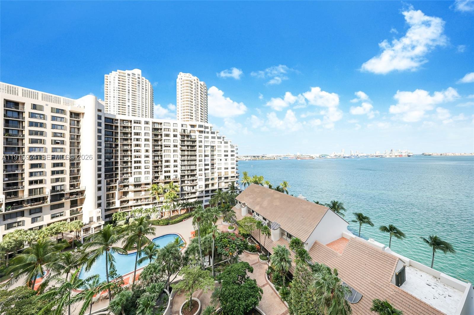 An elevated view shows a swimming pool, lush landscaping, and high-rise buildings beside the ocean — 520 Brickell Key Dr # A1104, Miami FL 33131, MIAMI, FL