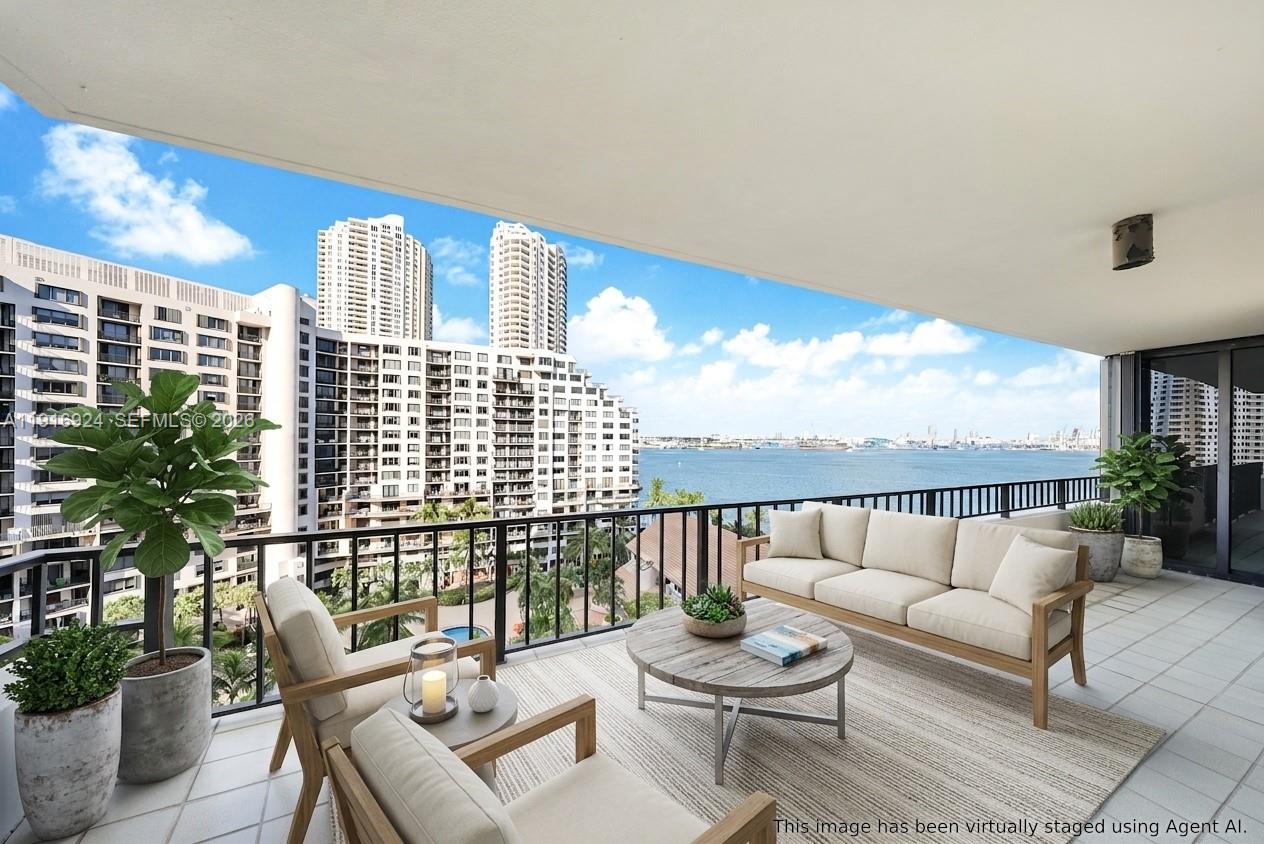 A virtually staged balcony with outdoor furniture overlooking a bay and high-rise buildings — 520 Brickell Key Dr # A1104, Miami FL 33131, MIAMI, FL