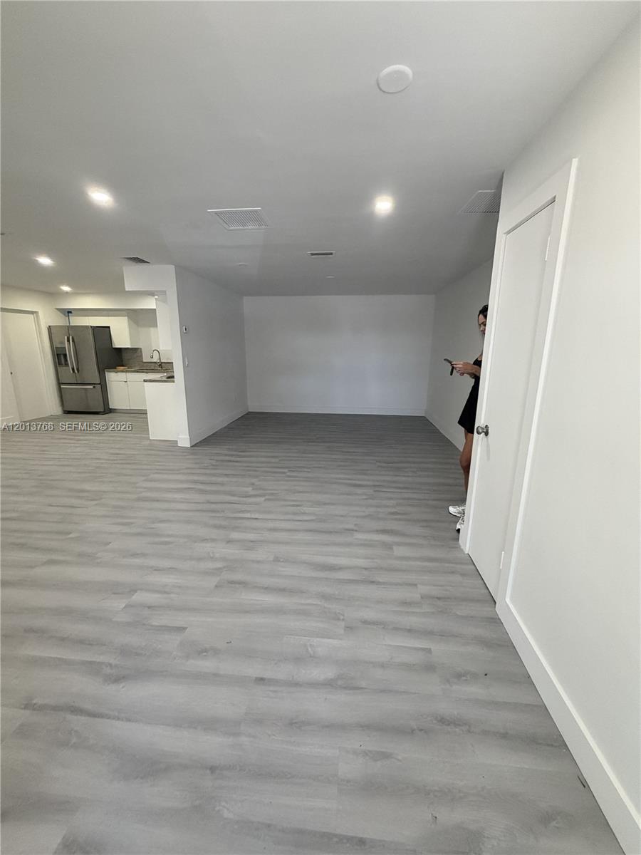 An open-concept living area features light gray wood-look flooring and a small adjacent kitchen — 9401 SW 64th Ter # 0, Miami FL 33173, MIAMI, FL