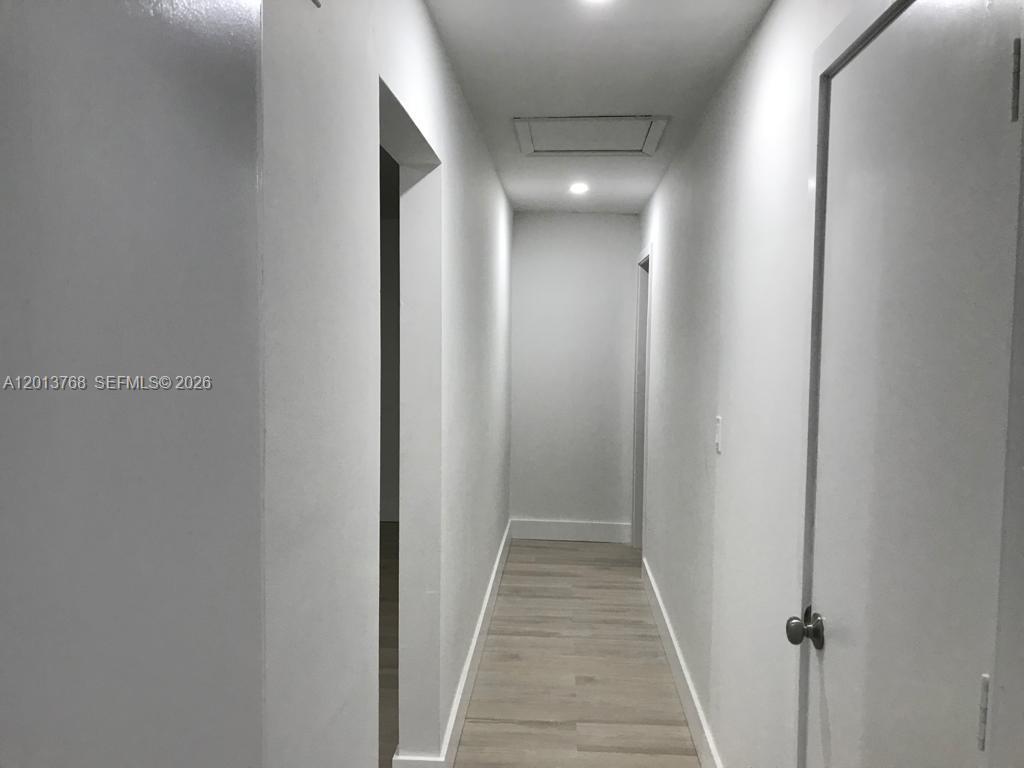 A narrow hallway features light-colored wood-look flooring, white walls, and two closed doors — 9401 SW 64th Ter # 0, Miami FL 33173, MIAMI, FL