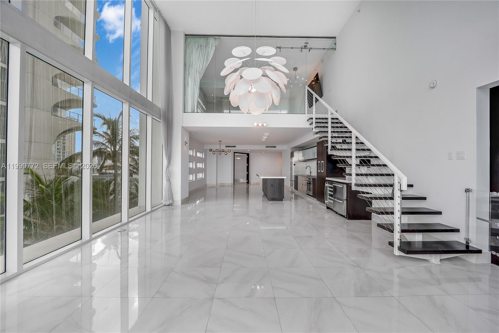 A modern, two-story living area features floor-to-ceiling windows, white marble flooring, and a staircase — 1040 Biscayne Blvd # 1001, Miami FL 33132, MIAMI, FL