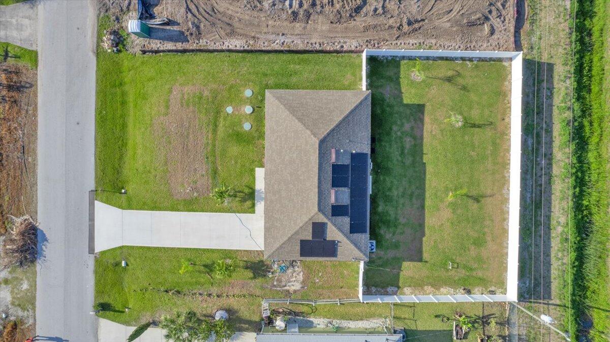 An aerial view shows a house with solar panels on its roof and a fenced yard — 3129 Wessel Avenue SE, Palm Bay FL 32909, PALM BAY, FL