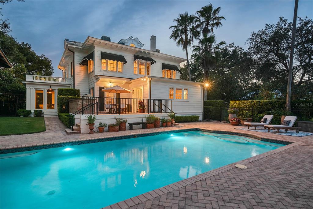 A two-story white house with a swimming pool and a brick patio at dusk — 705 DELANEY AVENUE, ORLANDO, FL