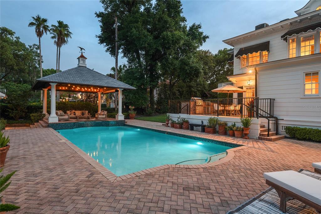 A swimming pool with a gazebo and a white house with a patio at dusk — 705 DELANEY AVENUE, ORLANDO, FL