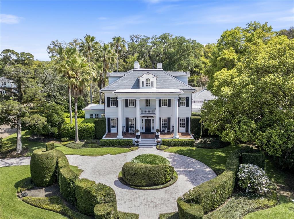 An aerial view of a white, two-story colonial-style house with a circular driveway and landscaping — 705 DELANEY AVENUE, ORLANDO, FL