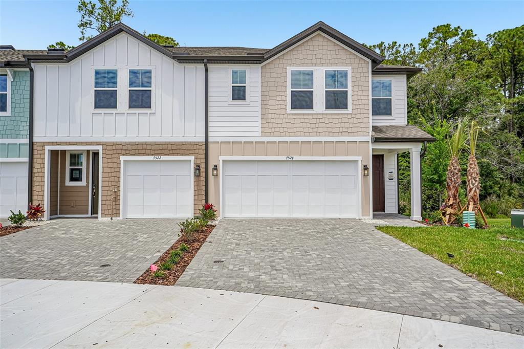 A two-story townhouse exterior features a two-car garage, stone-look siding, and a paved driveway — 7524 DEER VALLEY CIRCLE, TAMPA, FL