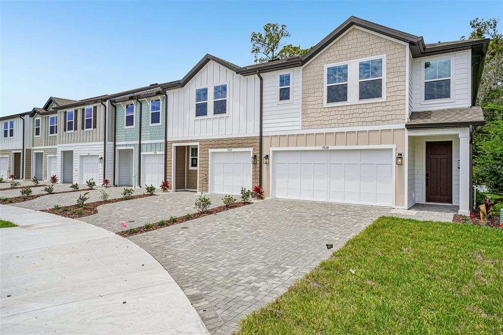 A row of modern townhouses features varied siding, paved driveways, and attached garages — 7524 DEER VALLEY CIRCLE, TAMPA, FL