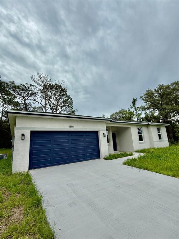 A single-story house with a blue garage door and a concrete driveway under a cloudy sky — 2190 W ARBUTUS DRIVE, CITRUS SPRINGS, FL
