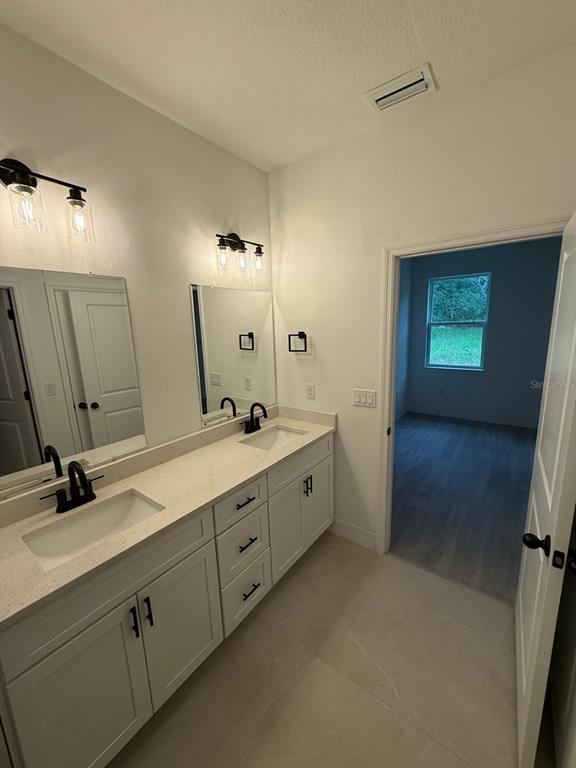 A bathroom features a double vanity with white cabinets, quartz countertops, and black fixtures — 2190 W ARBUTUS DRIVE, CITRUS SPRINGS, FL