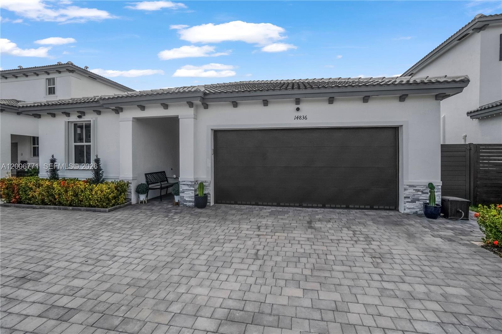 A white house exterior features a large dark garage door and a paved driveway — 14836 SW 162nd St, Miami FL 33187, MIAMI, FL
