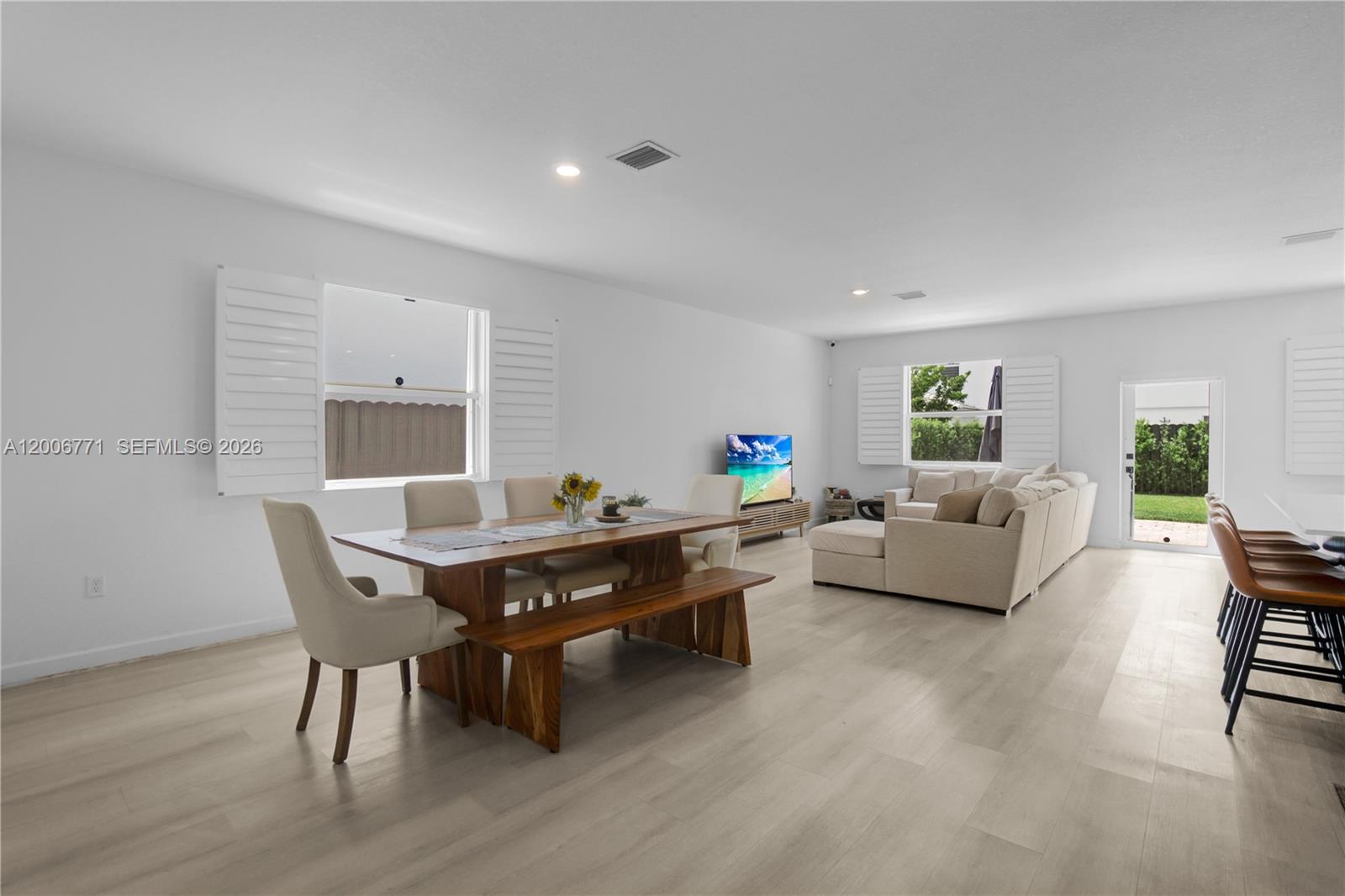 An open-concept living and dining area features light wood flooring and white walls — 14836 SW 162nd St, Miami FL 33187, MIAMI, FL