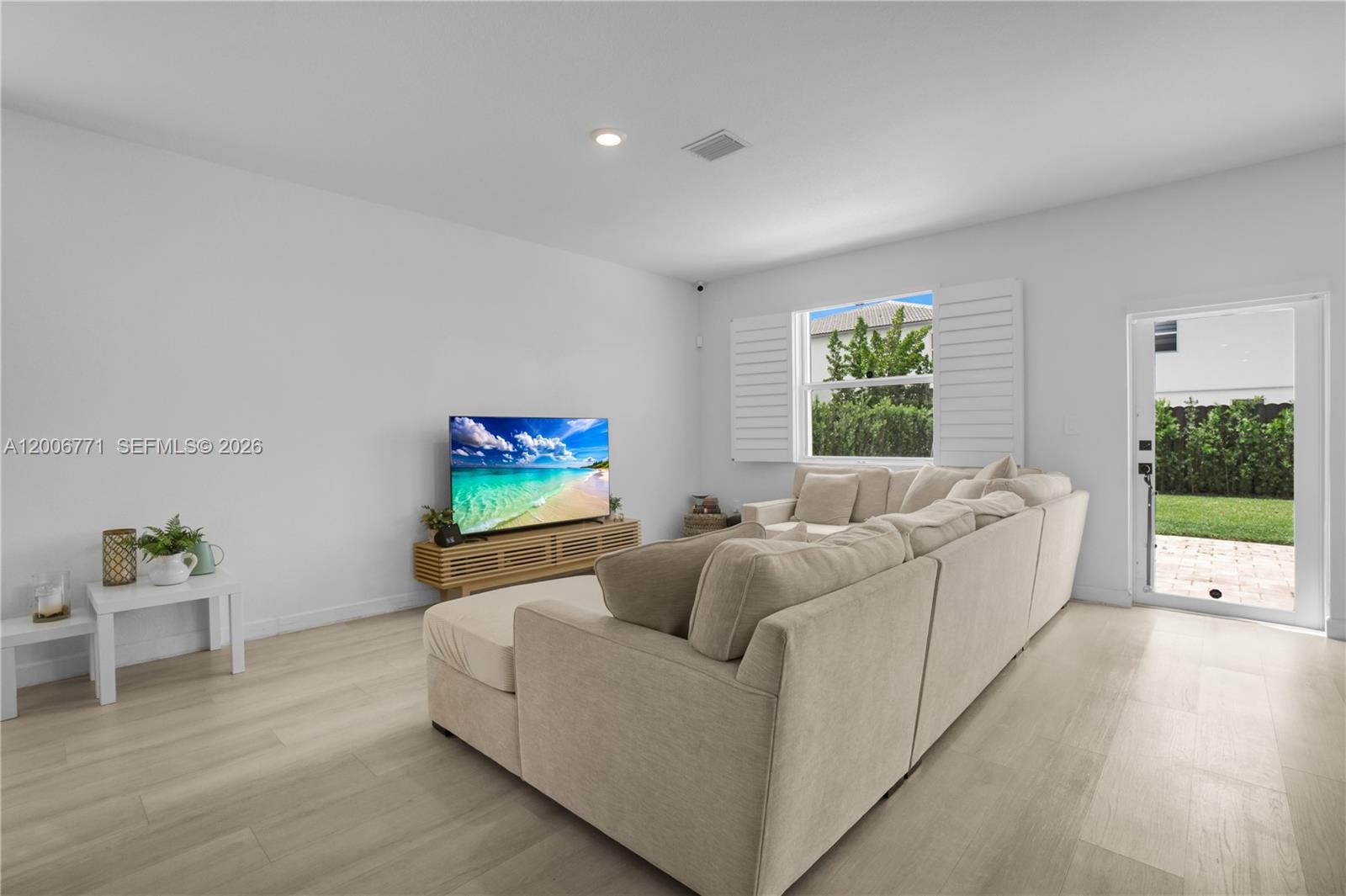 A living room features a beige sectional sofa, a television on a wooden stand, and a glass door — 14836 SW 162nd St, Miami FL 33187, MIAMI, FL