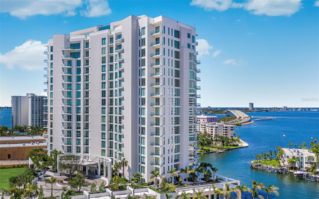 An aerial view of a tall white residential building situated along a waterfront — 401 QUAY COMMONS UNIT 1004, SARASOTA, FL