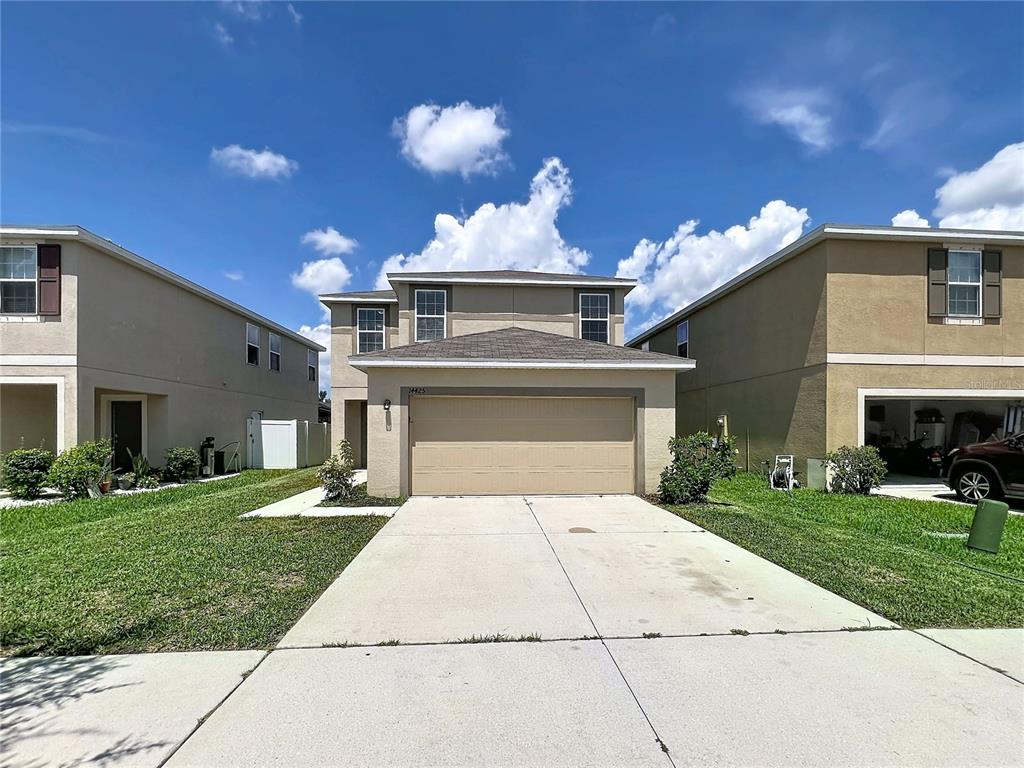 A two-story suburban house with a tan stucco exterior and a two-car garage — 14425 DUNROBIN DRIVE, WIMAUMA, FL