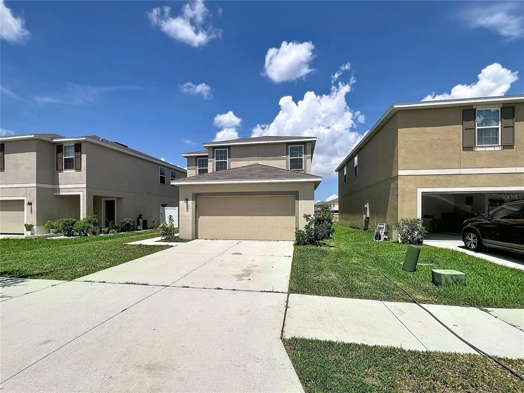 A two-story suburban house with a tan stucco exterior and a two-car garage — 14425 DUNROBIN DRIVE, WIMAUMA, FL