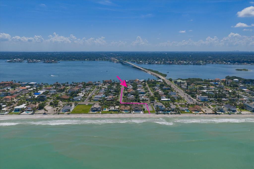 An aerial view shows a coastal neighborhood with a pink arrow pointing to a house — 114 13TH STREET, BELLEAIR BEACH, FL