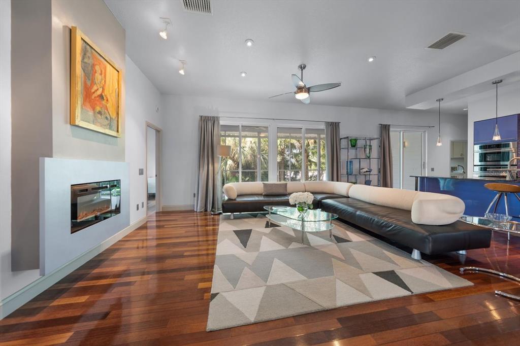 A modern living room features a fireplace, a large sectional sofa, and hardwood flooring — 114 13TH STREET, BELLEAIR BEACH, FL