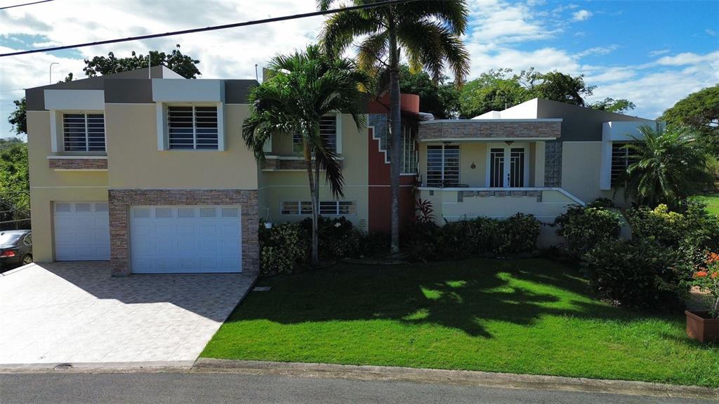 A two-story house with a white garage, stone accents, and a front lawn — 1117 CALLE VIRGINIA BARRETO GARCIA, QUEBRADILLAS, PR