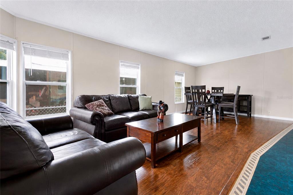 A living room with dark leather sofas, a wooden coffee table, and a dining area — 169 PINE TREE DRIVE, DEBARY, FL