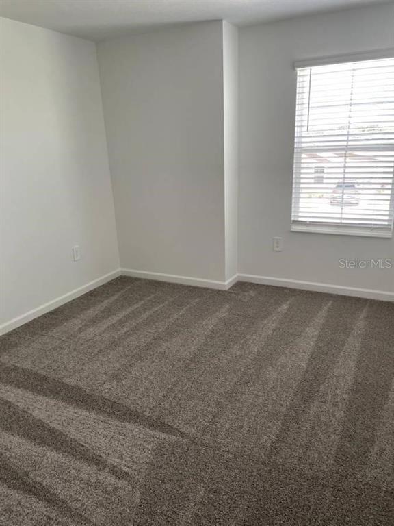 An empty bedroom features gray carpet, white walls, and a window with white blinds — 1642 TEAGAN LANE, WINTER HAVEN, FL