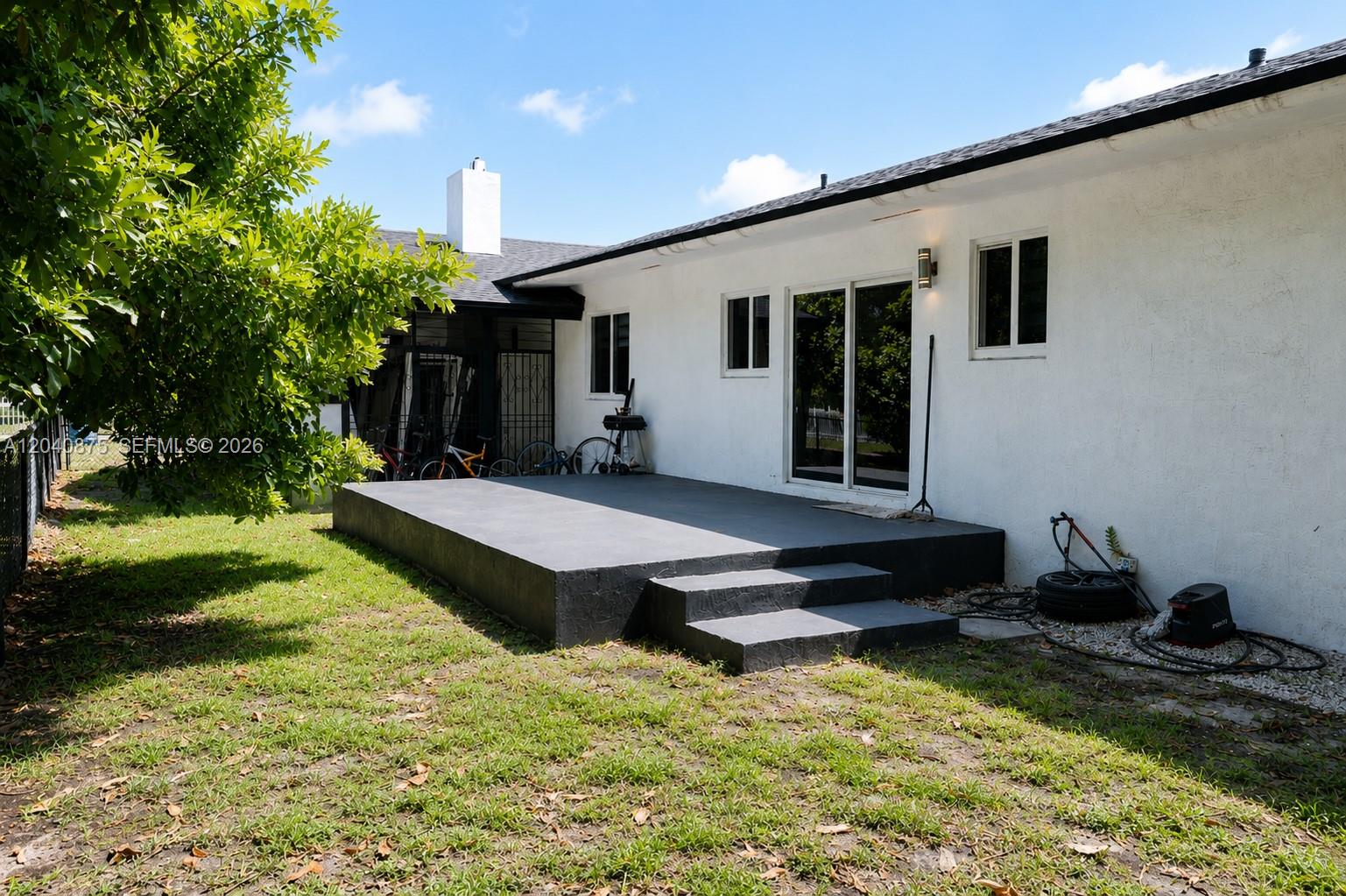 A white house exterior features a raised, dark gray concrete patio with steps — 1860 NW 81st St, Miami FL 33147, MIAMI, FL