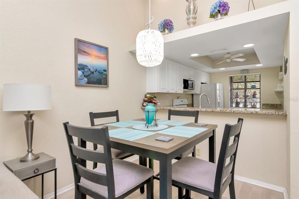 A dining area with a table, four chairs, and a pendant light near a kitchen — 11511 113TH STREET UNIT 13F, LARGO, FL