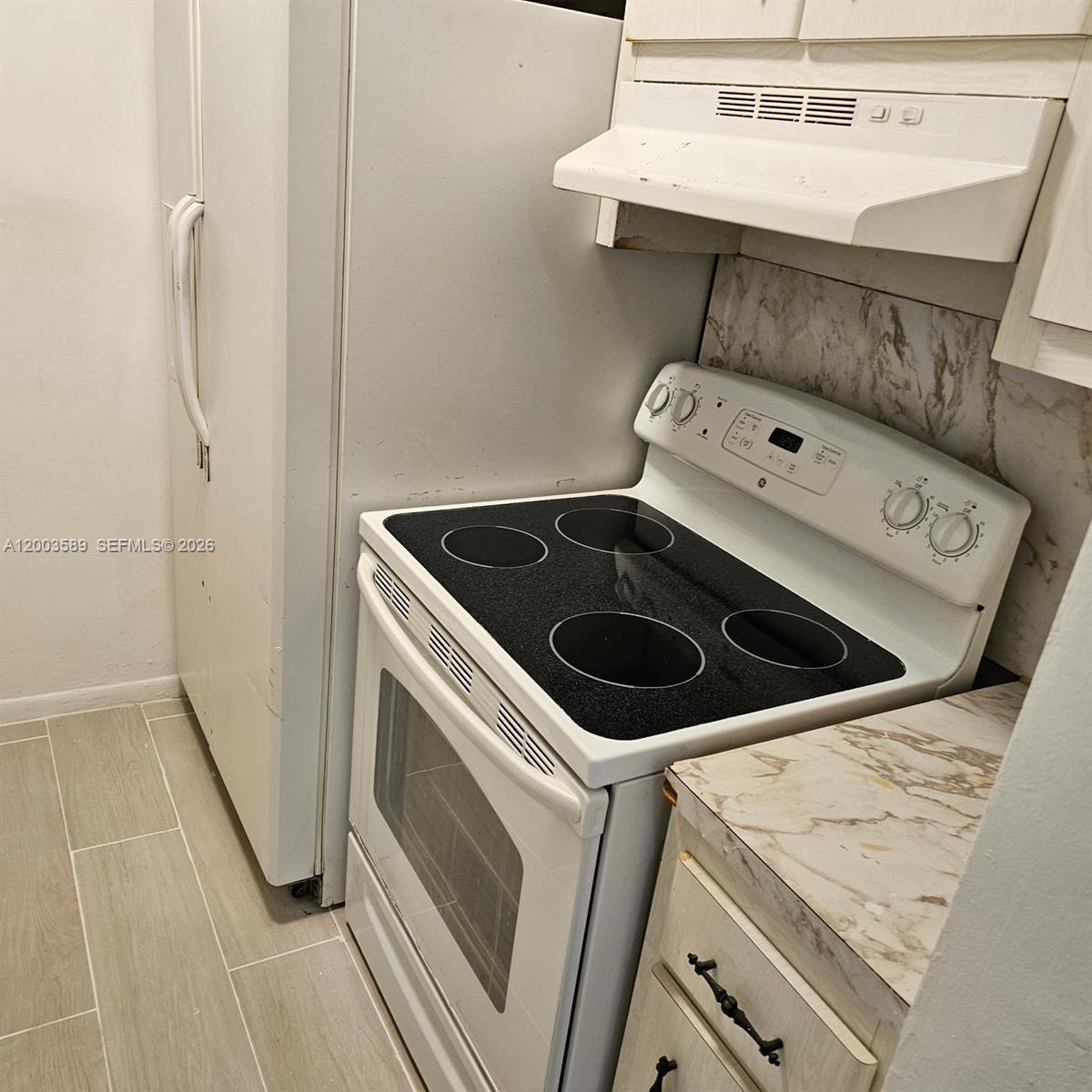 A white electric stove sits between a refrigerator and a counter with marble-patterned laminate — 230 SW 11th Ave # 14, Hallandale Beach FL 33009, HALLANDALE BEACH, FL