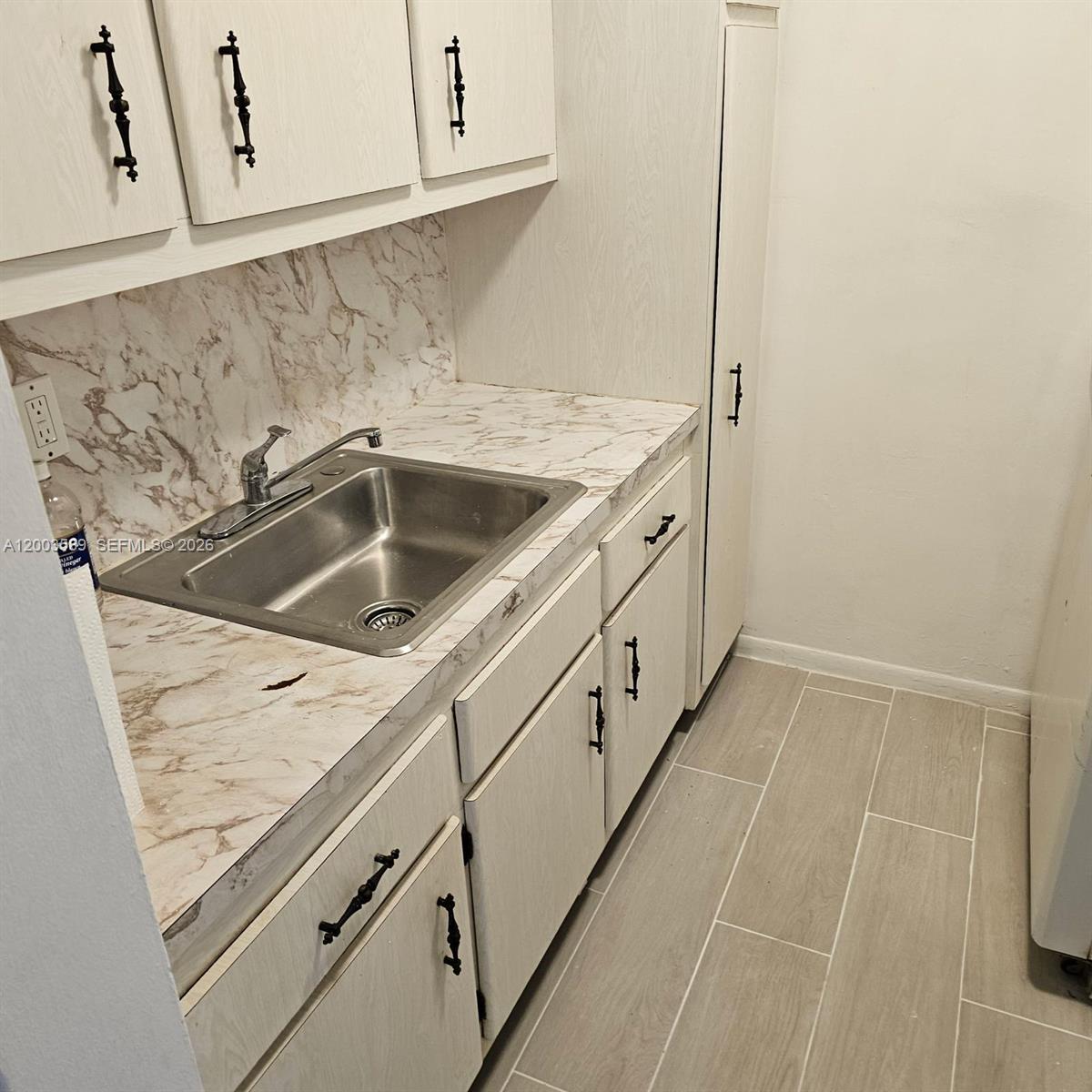A laundry room features a stainless steel sink, marble-patterned countertops, and light-colored cabinetry — 230 SW 11th Ave # 14, Hallandale Beach FL 33009, HALLANDALE BEACH, FL