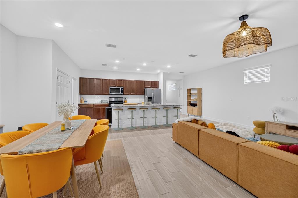 An open-concept kitchen, dining area, and living room featuring wood-toned cabinets and yellow chairs — 3231 NW 52ND AVENUE ROAD, OCALA, FL
