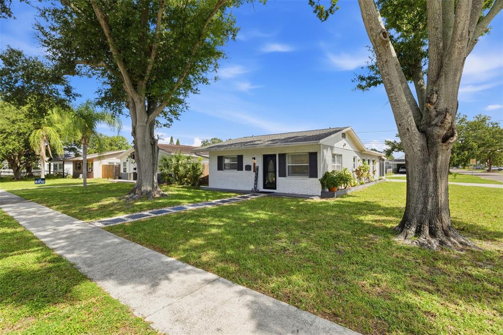 A single-story white brick house with a front walkway sits on a grassy lawn — 801 89TH AVENUE N, ST PETERSBURG, FL
