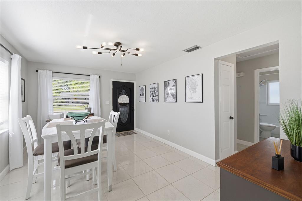 A dining area with a white table, chairs, tile flooring, and a modern light fixture — 801 89TH AVENUE N, ST PETERSBURG, FL