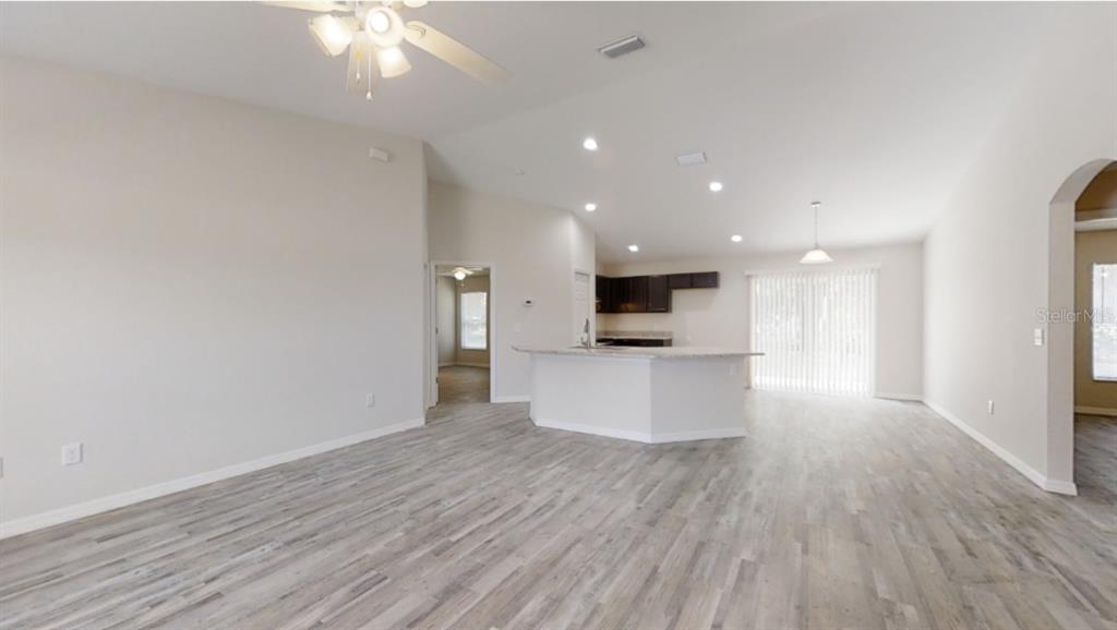 An open-concept living area features light wood-look flooring, a kitchen island, and recessed lighting — 12966 SW 86TH COURT, OCALA, FL