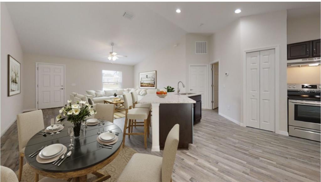 An open-concept kitchen, dining area, and living room featuring wood-look flooring and dark cabinetry — 12966 SW 86TH COURT, OCALA, FL