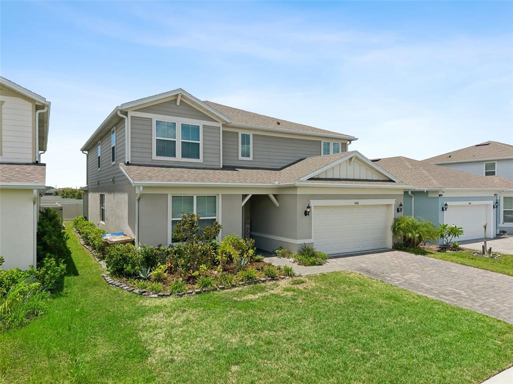 A two-story suburban house with gray siding, a paved driveway, and a front garden — 5668 ARBORVISTA STREET, ST CLOUD, FL