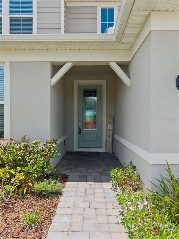 A paved walkway leads to a light green front door under a covered entryway — 5668 ARBORVISTA STREET, ST CLOUD, FL