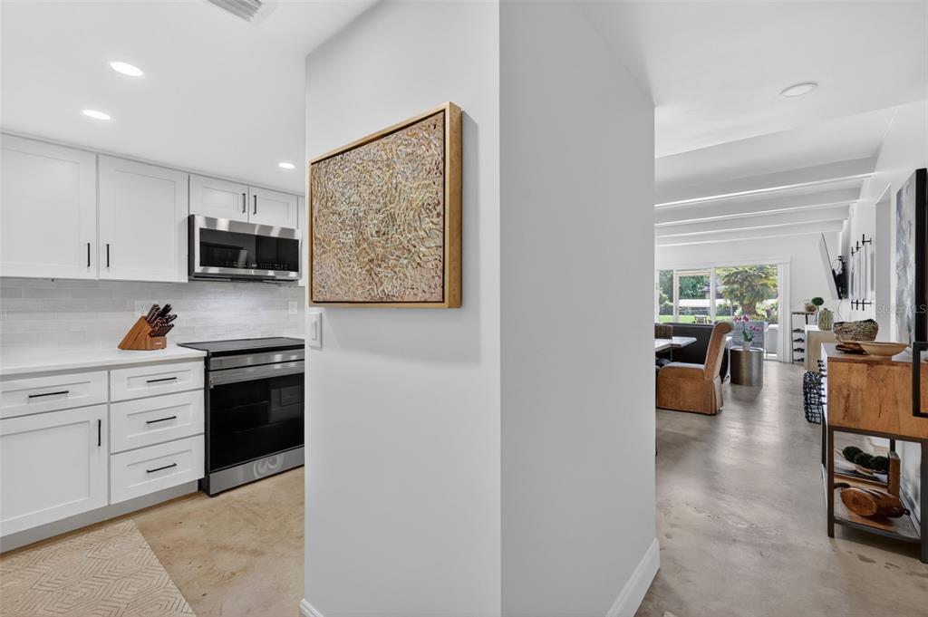 A white kitchen with stainless steel appliances opens into a living area with concrete floors — 101 N GRANDVIEW STREET UNIT 1, MOUNT DORA, FL