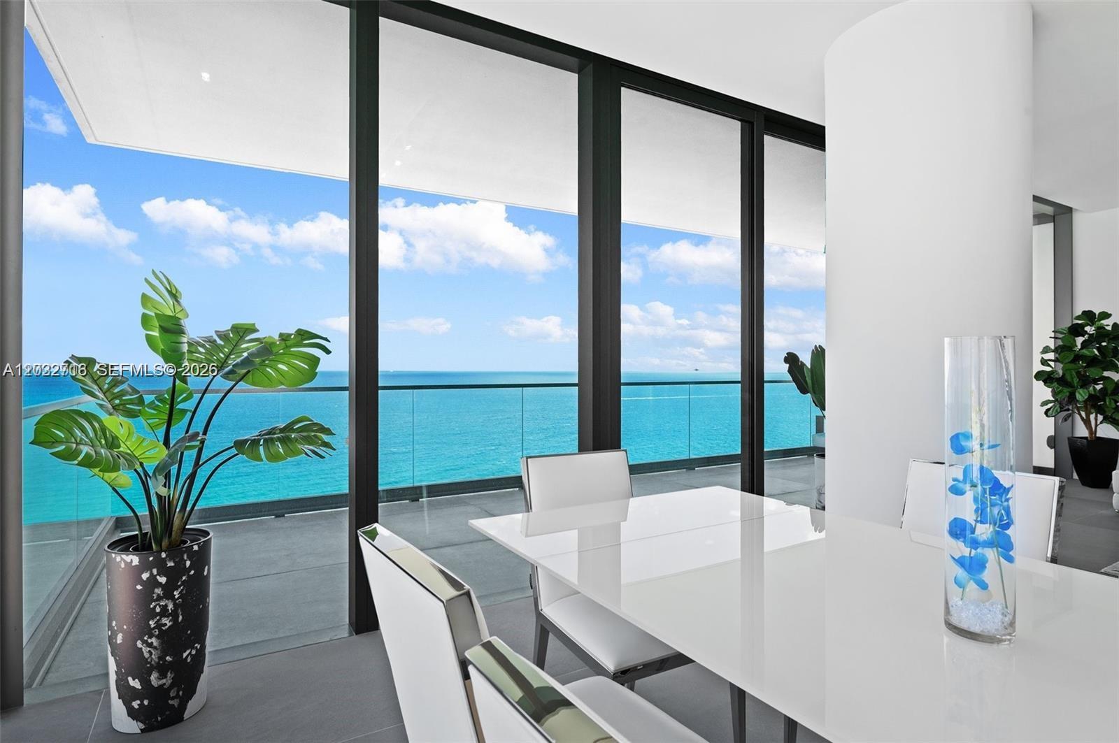 A dining area features a white table and chairs overlooking the ocean through floor-to-ceiling windows — 2000 S Ocean Dr # 25A, Hallandale Beach FL 33009, HALLANDALE BEACH, FL