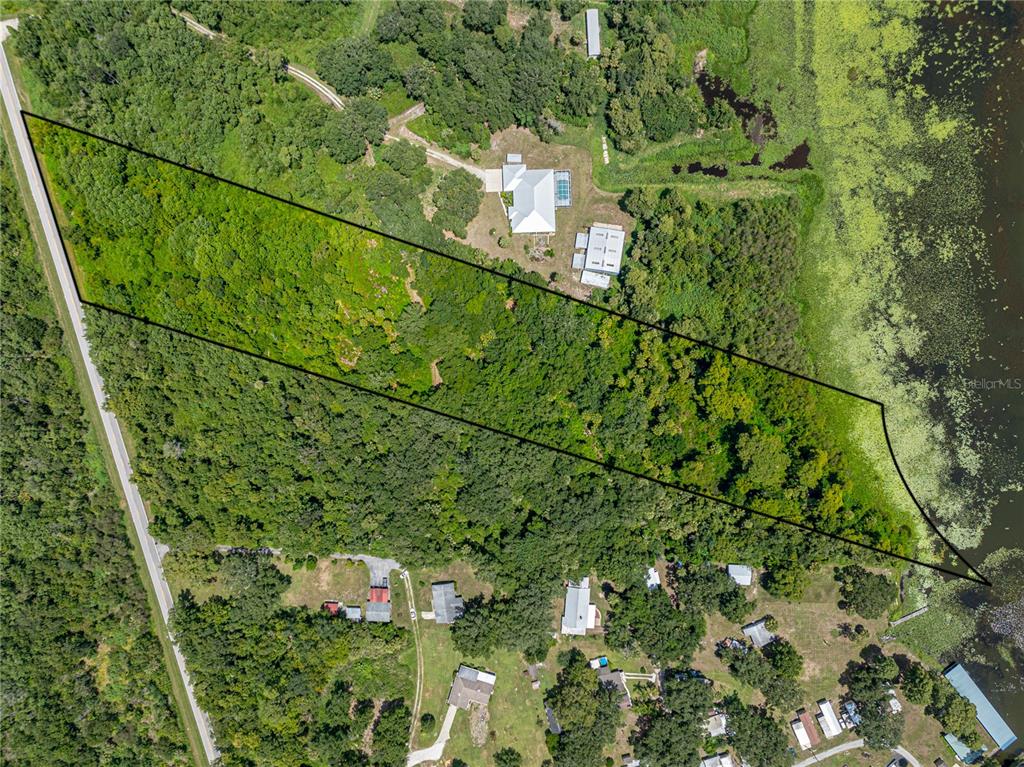 An aerial view shows a large, wooded plot of land outlined in black beside a lake — 0 TIMBERLANE ROAD, LAKE WALES, FL