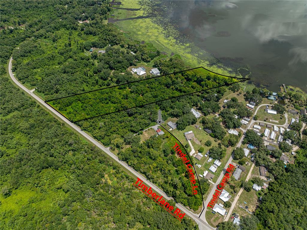 This aerial view shows a wooded property with a lakefront boundary and road access — 0 TIMBERLANE ROAD, LAKE WALES, FL