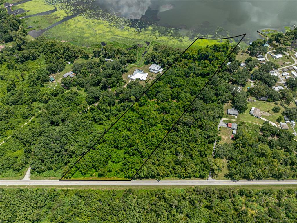 An aerial view shows a large, wooded plot of land bordering a lake — 0 TIMBERLANE ROAD, LAKE WALES, FL